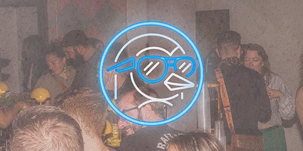 A lively bar scene with people socializing, featuring a neon bird logo wearing sunglasses.